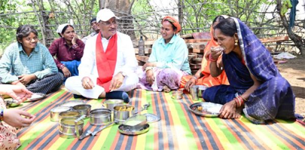 During the inspection of the under-construction Panchayat Bhawan, workers invited the Chief Minister for a meal: They sat together and ate Bore Basi and Aama Chutney.